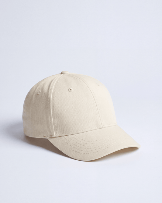 Cream cotton twill cap at three quarters, showing the topstitched curved brim and self fabric eyelets